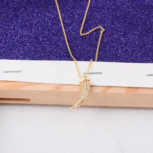 Close-up detail of a 18K gold plated horn shaped pendant with micro-pave crystals