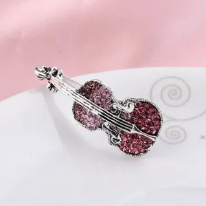 Macro detail of vintage silver violin brooch with pink rhinestones on white plate