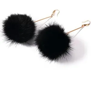 Detailansicht eleganter schwarzer Pompon-Ohrringe mit goldenen Fischhaken-Drähten