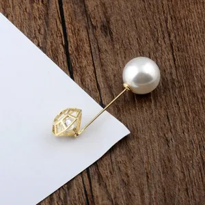 Detailansicht der 14K vergoldeten Brosche mit Zirkon und Perle auf Holzoberfläche