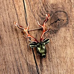 Detailed view of a vintage stag head brooch with orange antlers on a wood background
