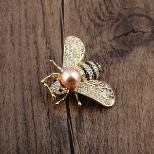 Detailaufnahme einer goldenen Bienenbrosche mit rosa Perle und Glitzersteinen