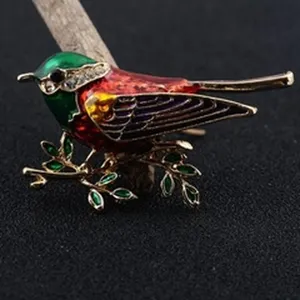 Vibrant colorful enameled bird brooch featuring rhinestone accents and delicate leaf details