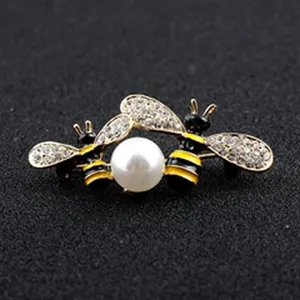Detailed view of golden honeybee brooch featuring white pearl and sparkling rhinestone wings.