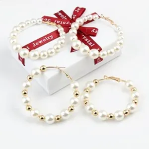 Elegante Perlenohrringe mit goldenen Perlen auf einer weißen Schmuck-Geschenkbox