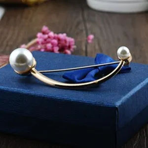 Detailansicht einer eleganten Brosche mit zwei Perlen auf einer blauen Schmuckschatulle.