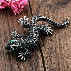 High-quality close-up detail of a vintage gecko brooch with black crystals and green eyes.