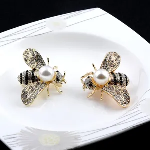 Detailaufnahme von zwei eleganten goldenen Bienenbroschen mit Perlen und Strass