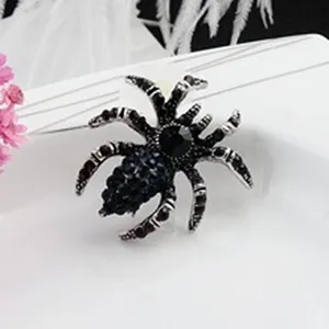 Close-up of a sparkling spider brooch pin with black rhinestones on a white background.