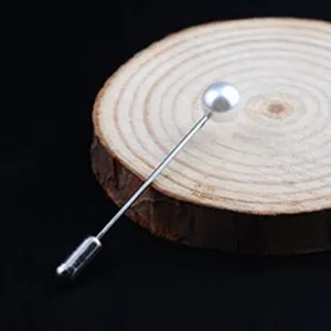 Nahaufnahme einer eleganten weißen Perlen-Anstecknadel auf einer rustikalen Holzscheibe