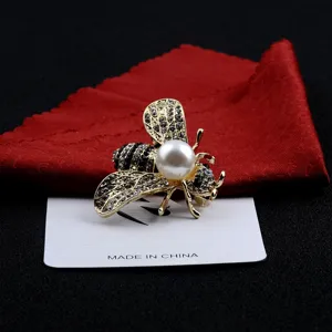 Detailaufnahme einer goldenen Bienenbrosche mit großer Perle und schwarzen Strasssteinen
