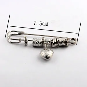 Detailed view of a vintage silver heart brooch with charms and 7.5cm size indicator