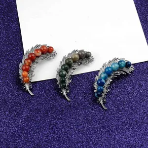 Close-up detail of three feather-shaped natural stone brooches in vibrant colors.