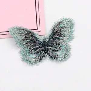 Vista detallada de un parche de mariposa bordado azul claro con flecos de hilo metálico