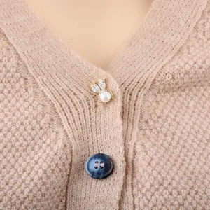 Detailansicht einer süßen Hasenperlenbrosche an einer beige gestrickten Strickjacke.