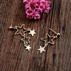 Detailansicht goldener Sternohrringe mit hohlen und massiven Sternen auf Holzoberfläche
