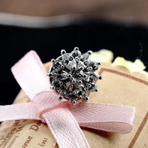 Nahaufnahme einer funkelnden blumenförmigen Brosche mit klaren Steinen auf einem Geschenkanhänger