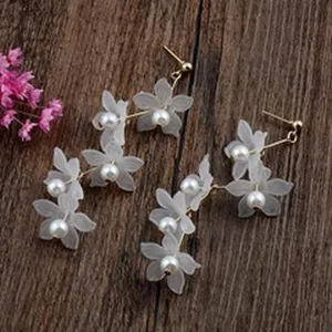 Detailansicht eleganter weißer Blumenohrringe mit Perlen auf einem dunklen Holzhintergrund
