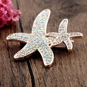 Nahaufnahme einer glitzernden Seestern-Brosche in Roségold mit Kristallen.