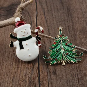 Detailaufnahme von Weihnachtsbroschen mit einem Emaille-Schneemann und Tannenbaum