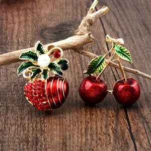 Detailaufnahme von eleganten Apfel- und Kirschen-Broschen mit roten Strasssteinen