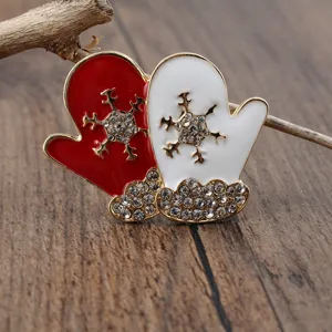 Nahaufnahme von rot-weißen Weihnachts-Fäustling-Broschen mit Schneeflocken-Strass-Details