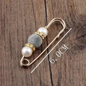 Detail view of a 6.0cm safety pin brooch with grey flocked and white pearl beads