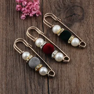 Detail of three gold-tone safety pin brooches with pearls and colorful flocked beads