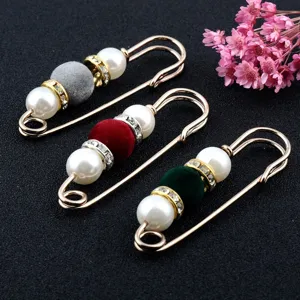 Close-up view of three safety pin brooches featuring colorful flocked beads and pearls