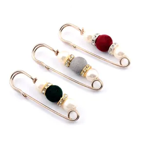 Macro detail showing three rose gold safety pin brooches with pearls and flocked beads.
