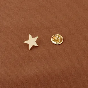 Macro view of golden star-shaped brooch with metal clutch backing on textured background