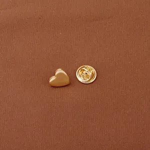 Detailed close-up of a glossy gold heart-shaped mini lapel pin with butterfly clutch backing