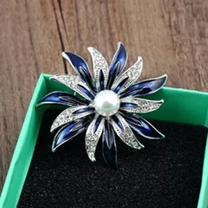 Detailopname van een blauwe emaille bloembroche met strass en parel