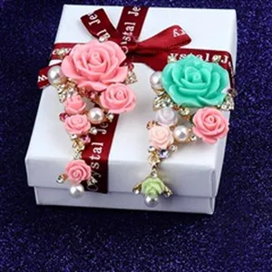 Detail van elegante roze en turquoise hars roos broches op een witte geschenkdoos
