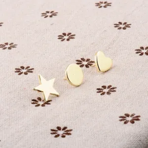 Detail shot of mini gold geometric heart, star, and oval pins on patterned fabric.