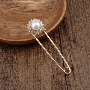 Detailansicht einer eleganten goldenen Brosche mit Perle und Strasssteinen