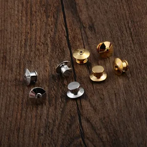 Detailed view of metal locking pin backs in gold and silver plating on wood background
