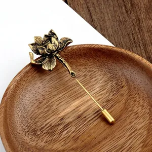 Detail van een vintage lotus sierspeld op een rustieke houten schotel accessoire