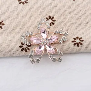 Détail d'une broche florale avec des pétales en cristal rose et des strass blancs