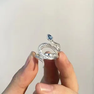 Silver snake ring with blue topaz gemstone, adjustable open band, elegant animal jewelry design.