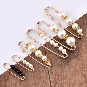 Detalle de elegantes imperdibles con perlas y pedrería para ajuste de cintura y fijación.