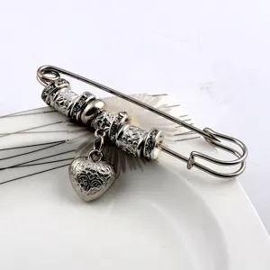 Close-up of vintage silver-tone heart charm safety pin brooch with intricate floral engravings