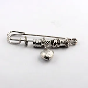 Close-up of vintage heart charm safety pin brooch with decorative beads and crystals