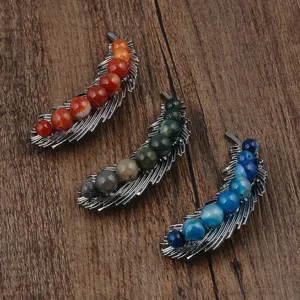 Detailed macro shot of three feather-shaped brooches with colorful natural stones