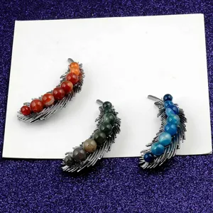 Detailed macro shot showing feather-shaped brooches with vibrant natural stone beads