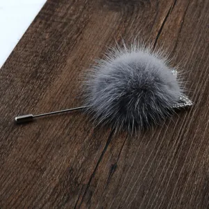 Detailansicht der grauen Nerzfell-Pompon-Brosche mit Strass-Hasenohren auf Holzgrund