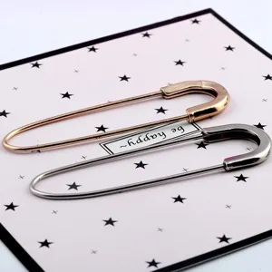 Close-up of decorative oversized safety pin brooches in rose gold and silver metallic finishes