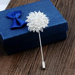 Elegant handmade white pearl flower brooch pin displayed on a blue gift box surface