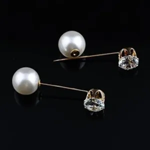 Detail view of gold-tone needle brooch with white faux pearl and clear crystal accent