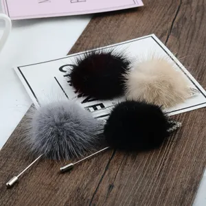 Detailansicht von vier luxuriösen Nerzpelz-Bommel-Broschen in Grau, Rot, Beige und Schwarz.